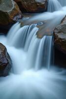 A waterfall flowing over rocks in a stream photo