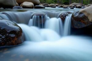 A stream of water flows over rocks in a forest photo