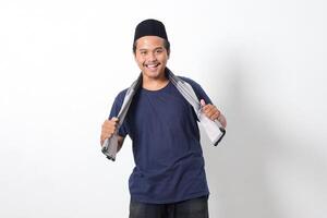 Portrait of confident Asian muslim man wearing scarf and skullcap standing with cool pose and holding his sarung. Isolated image on white background photo