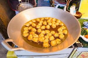 Traditional Thai Fish Cakes Frying in a Hot, Oily Pan at a Local Market Stall, Showcasing Authentic Street Food with Golden-Brown, Crispy Texture photo