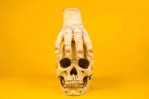 Severed Hand on a Skull Against a Yellow Background.Artistic and Spooky Halloween-Themed Display photo