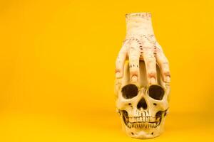 Severed Hand on a Skull Against a Yellow Background.Artistic and Spooky Halloween-Themed Display photo