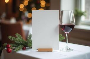 Elegant table setting featuring a blank menu card in a wooden holder and a glass of red wine. a festive Christmas background. Happy New Year photo