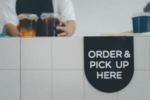 Order and pick up here sign on the counter bar with barista put two iced coffees photo