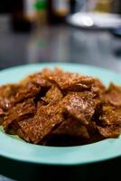 Sliced sheets of dried and crispy pork on dish. photo