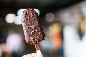 Chocolate popsicle ice cream bar with crushed peanut nuts. photo