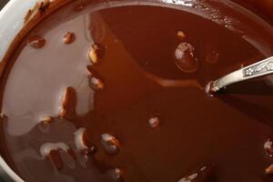 Powdered sugar, cocoa butter and grated cocoa in a container for making chocolate are heated in a water bath. photo