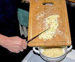 The hands of the cook pour the crushed cocoa butter into a container for making chocolate. photo