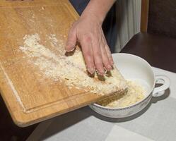 The hands of the cook pour the crushed cocoa butter into a container for making chocolate. photo