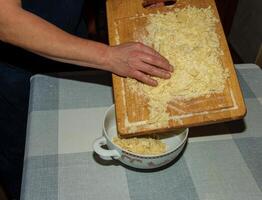 The hands of the cook pour the crushed cocoa butter into a container for making chocolate. photo