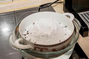 Powdered sugar, cocoa butter and grated cocoa in a container for making chocolate are heated in a water bath. photo