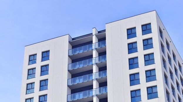 moderno Alto Departamento edificio en blanco, estar alto en contra un azul cielo, ejemplificando innovador urbano arquitectura con pulcro, angular diseños foto