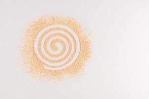 Dry loose powder of natural tone is scattered on a white background in a spiral. Abstract cosmetic background. A copy space. top view. Sample, Mockup photo