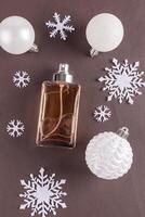 A chic bottle of expensive perfume on a leather brown background with white balls and snowflakes. Blank mockup . template. top vertical view. photo
