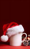 A red santa cap is on a white coffee mug with a dark background representing Christmas photo