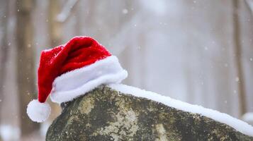 A red santa cap is on a stone or rock with a beautiful winter snowfall background photo