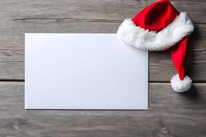 A blank white greeting card mockup along with red santa cap is placed on wooden background representing Christmas photo