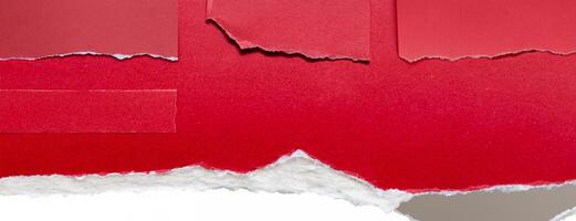 Close-up of a torn red paper edge on a white background, showing a rough texture and contrasting colors. photo