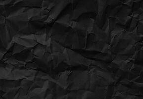Crumpled black paper texture with wrinkles and folds, ideal for backgrounds and design elements. photo