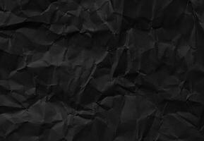 Crumpled black paper texture with wrinkles and folds, ideal for backgrounds and design elements. photo