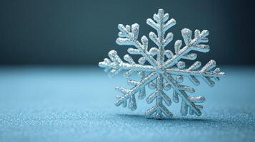 A unique snowflake stands out against a soft blue background, illustrating winter's charm photo