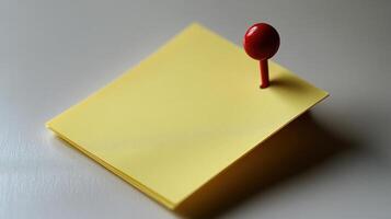 A cheerful yellow sticky note is secured by a bold red pushpin, creating visual interest photo