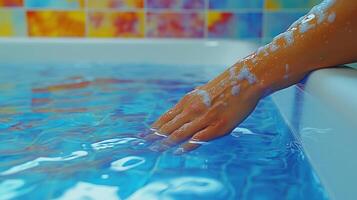Gentle fingers glide through crystal-clear water, surrounded by vibrant tiles photo