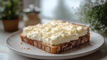 A thick layer of creamy spread on warm bread sits invitingly on a wooden table photo