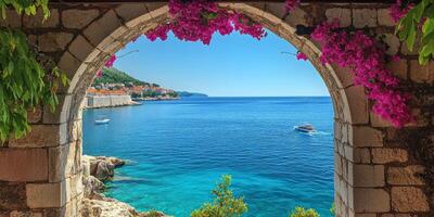 A breathtaking view of the azure sea framed by vibrant pink flowers and ancient stone architecture, epitomizing Mediterranean charm photo