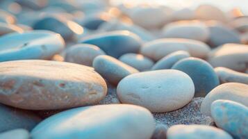 Close-up of smooth, multicolored pebbles on a sandy beach during sunset, creating a serene coastal ambiance. photo