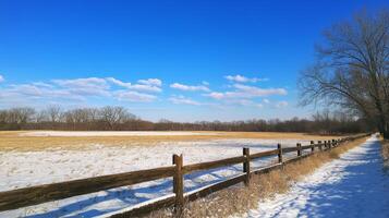 This picturesque scene showcases a snowcovered field, accented by a rustic wooden fence against a bright blue sky, ideal for capturing seasonal themes and enchanting outdoor imagery photo