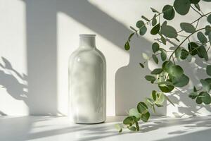 A serene display features a delicate white vase casting soft shadows, complemented by vibrant greenery against a neutral backdrop, embodying modern aesthetics and sustainability in design photo