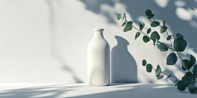 This minimalist display shows a bright white bottle casting subtle shadows, complemented by lush green leaves, creating an inviting atmosphere and promoting a serene, sustainable aesthetic photo