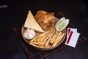 Grill Chicken with Toasted Bread, tomato, onion, lettuce leave, capsicum, french fries and salad served in wooden plate isolated on dark background side view of bangladeshi fast food photo