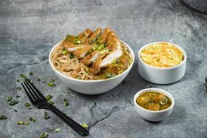 Katsu Chicken Noodles with potato curry, cabbage salad, green onion and fork served in bowl isolated on grey background side view of Japanese food photo