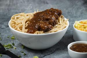 Kam heong chicken noodles with chili sauce, green onion and fork served in bowl isolated on grey background side view of asian food photo