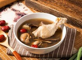Medicinal chicken leg soup with red jujube dates and spoon served in bowl isolated on napkin side view of taiwan food photo