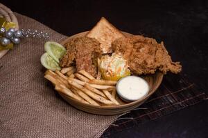 broasted chicken with French Fries, Toasted Bread and Salad served in wooden plate isolated on dark background side view of bangladeshi fast food photo