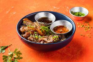 Garlic Rosemary Chicken Rice Bowl with Sauces, Green Onion and Coriander isolated on orange background side view of Appetizer Meal photo