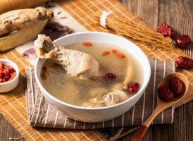 Ginseng Glutinous Rice Chicken Soup with red jujube dates and spoon served in bowl isolated on napkin side view of taiwan food photo