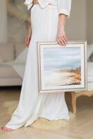 A woman is holding a beautiful painted picture in her hands. photo