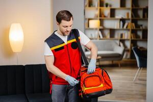 First aid course. A young male paramedic with a bag on his shoulders is standing in a classroom before a lecture photo