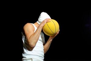 A basketball player in a white outfit poses confidently with a yellow ball in night park photo