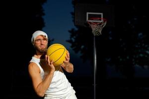 Man holding a basketball in a park at dusk, showcasing athleticism and confidence by the court photo