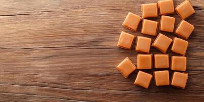 Square caramel candies stacked in a crisscross pattern on wooden surface photo