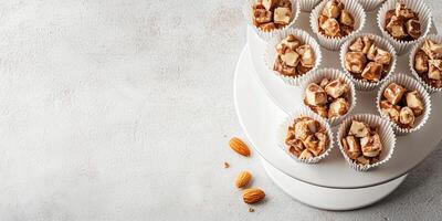 Chunks of almond toffee in paper cups on tiered stand photo