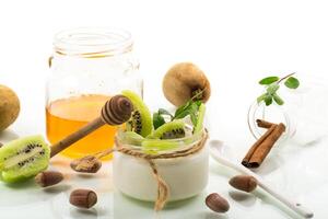 Homemade yogurt in a glass jar with honey, kiwi, nuts. Isolated on white photo