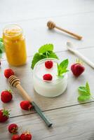homemade sweet yogurt in a jar with strawberries, on a wooden table photo