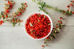 fresh ripe red goji berries in a bowl on a wooden table photo