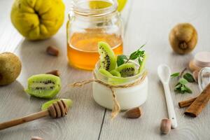 Homemade yogurt in a glass jar with honey, kiwi, nuts. photo